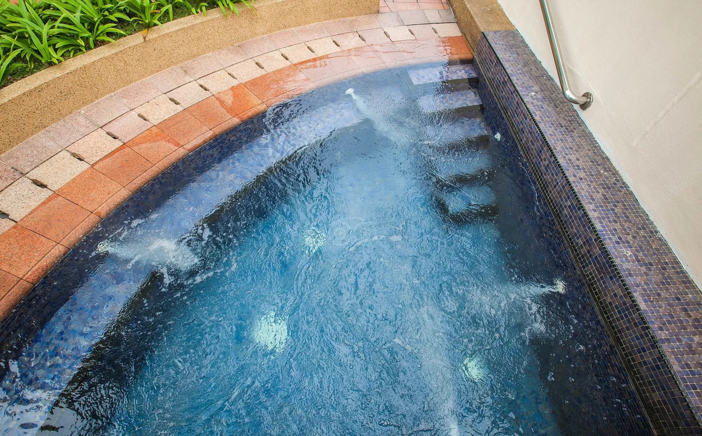 Clean pool water against a tiled and brick-edged surround